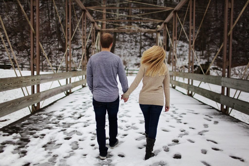 Couple walking on a bridge seen from behind Hiring Your Couples Counselor Therapist