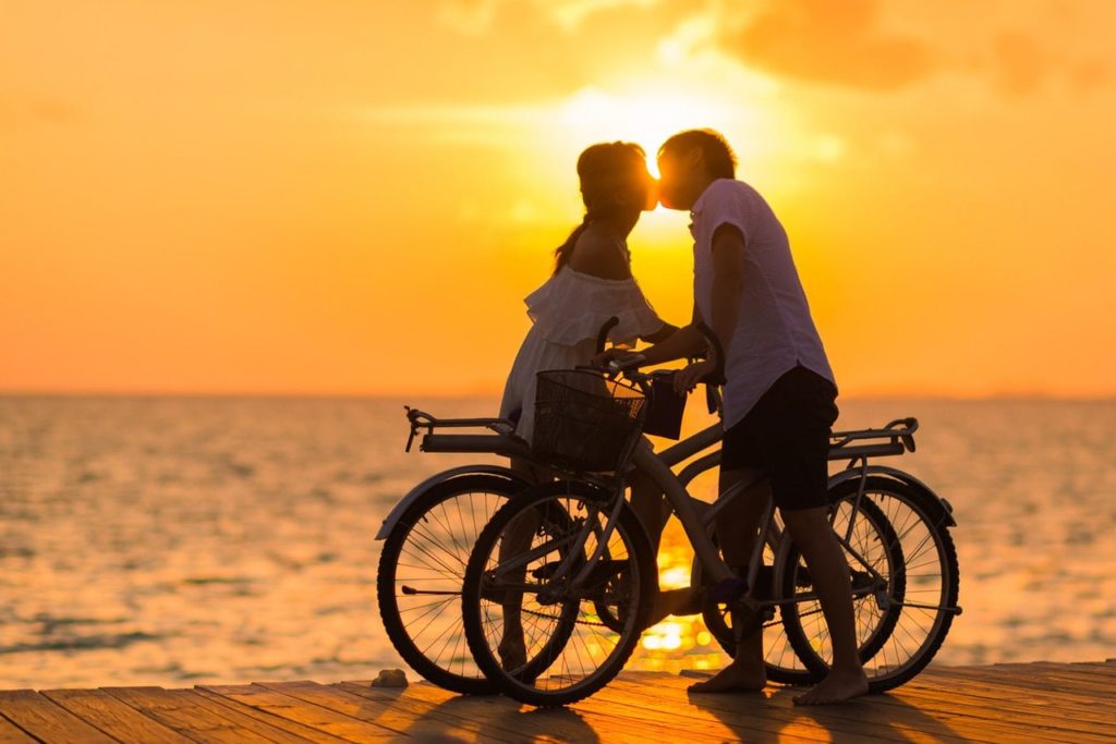 Loving Marriage Partners with Bikes in Sunset Kiss Loving Marriage Partners with Bikes in Sunset Kiss